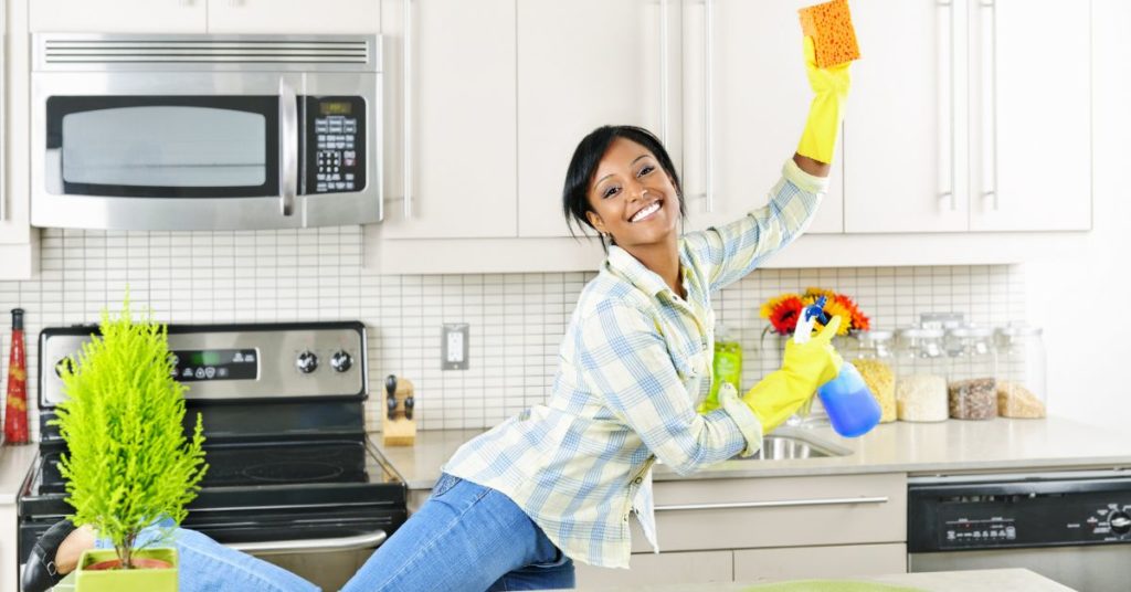Woman dancing while cleaning her kitchen