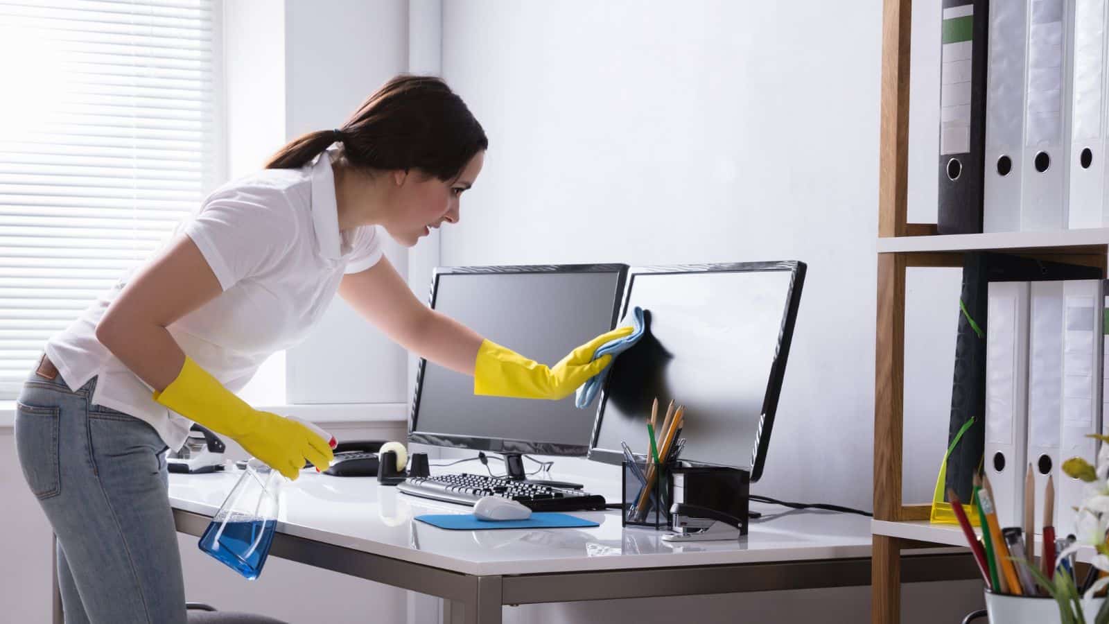 woman dusting computer monitors