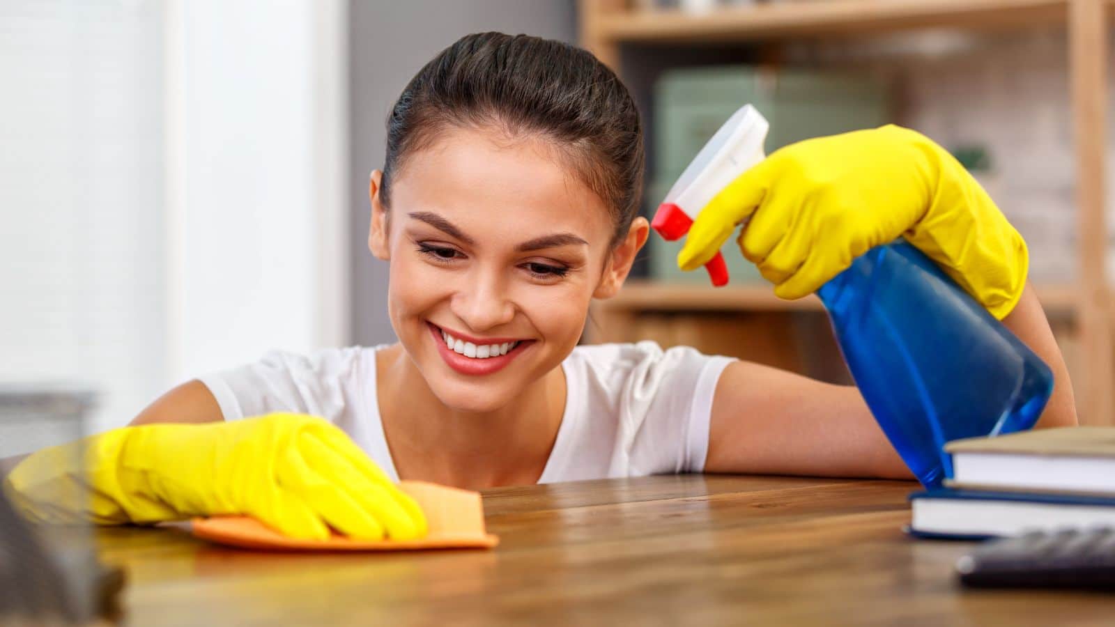 woman with yellow gloves cleaning a desk